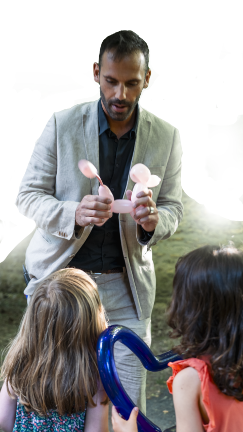 Benjamin réalisant des sculptures sur ballon pour des enfants émerveillés